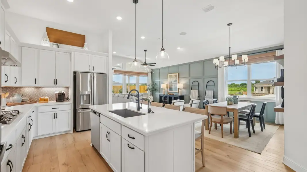 Elegant kitchen with gray scalloped backsplash, glass pendant lighting, center island, and ambient accent lighting Elegant kitchen with gray scalloped backsplash, glass pendant lighting, center island, and ambient accent lighting