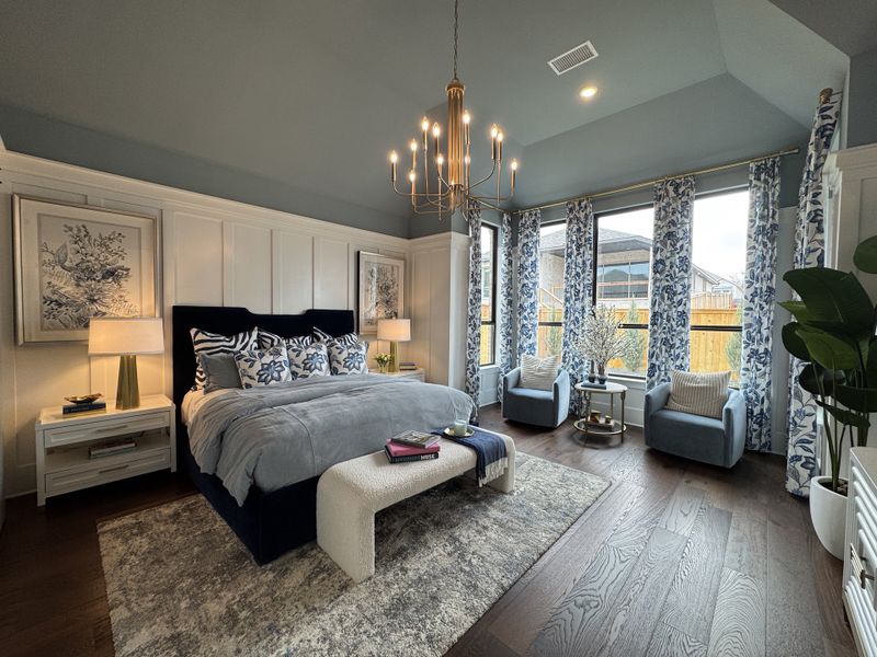 A luxurious bedroom featuring elegant furnishings, a plush bed, chic lighting, and large windows with floral curtains.