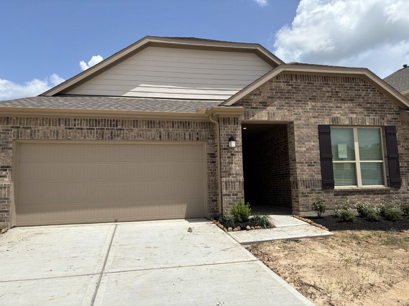 A charming brick home with a spacious garage and landscaped entry in Breckenridge Forest by KB Home (Spring, TX).