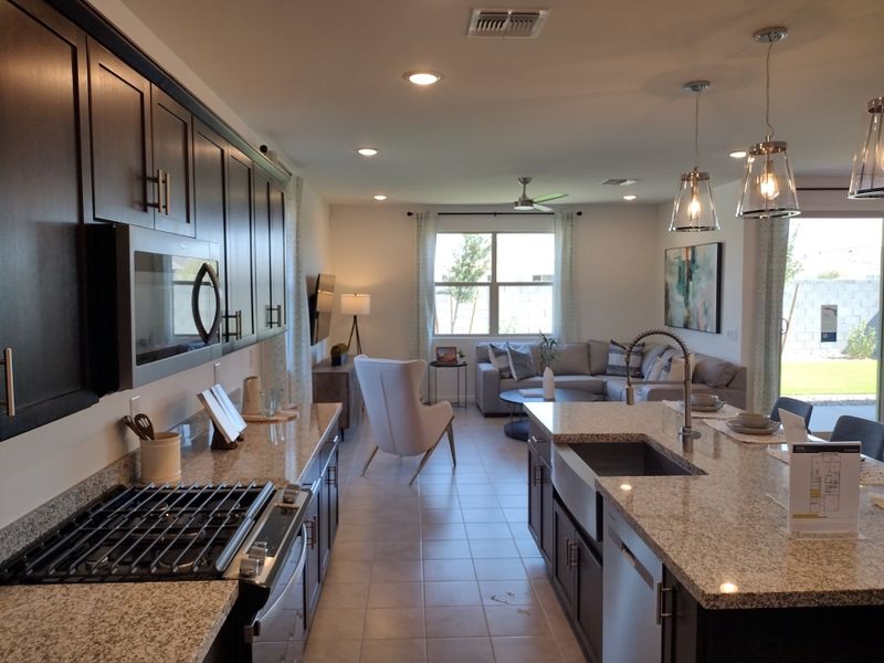 A modern kitchen and living area featuring granite countertops, dark cabinets, and stylish pendant lighting. A modern kitchen and living area featuring granite countertops, dark cabinets, and stylish pendant lighting.