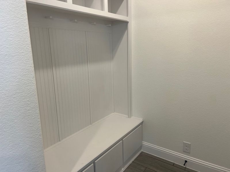 A sleek white mudroom with beadboard paneling, built-in bench, and storage hooks for organization and functionality. A sleek white mudroom with beadboard paneling, built-in bench, and storage hooks for organization and functionality.