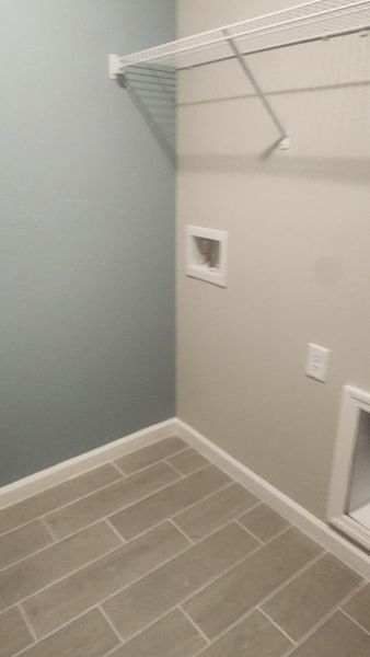 A sleek utility room featuring neutral walls, tiled flooring, and wire shelving for convenient storage.