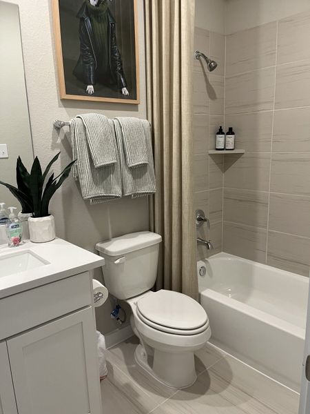 A modern bathroom featuring a white vanity, sleek fixtures, and tasteful wall art, creating a cozy and inviting atmosphere.