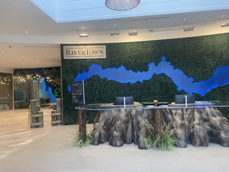 A modern lobby with a nature-inspired theme featuring a unique tree trunk desk and lush greenery. A modern lobby with a nature-inspired theme featuring a unique tree trunk desk and lush greenery.