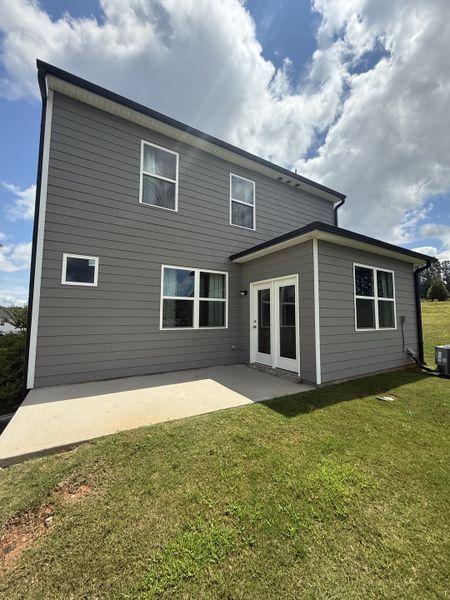 A modern grey home with large windows and a spacious backyard patio in Poplar Preserve by D.R. Horton (Newnan, GA).