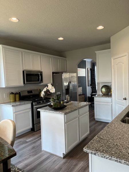 A modern kitchen with granite countertops, white cabinets, and stainless steel appliances. A modern kitchen with granite countertops, white cabinets, and stainless steel appliances.