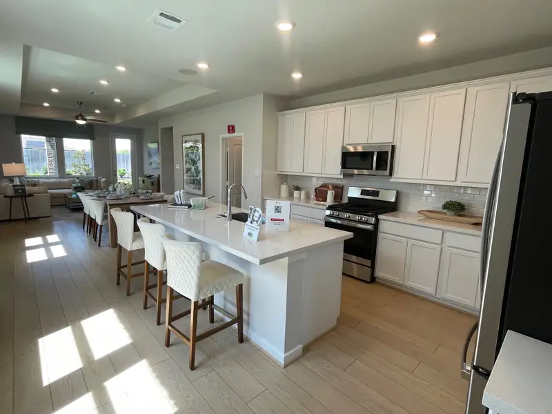 A modern kitchen with a sleek island, white cabinetry, stainless appliances, and abundant natural light.