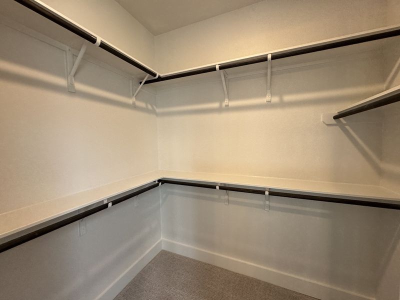 A spacious walk-in closet with ample shelving and hanging space, featuring neutral tones and clean design. A spacious walk-in closet with ample shelving and hanging space, featuring neutral tones and clean design.