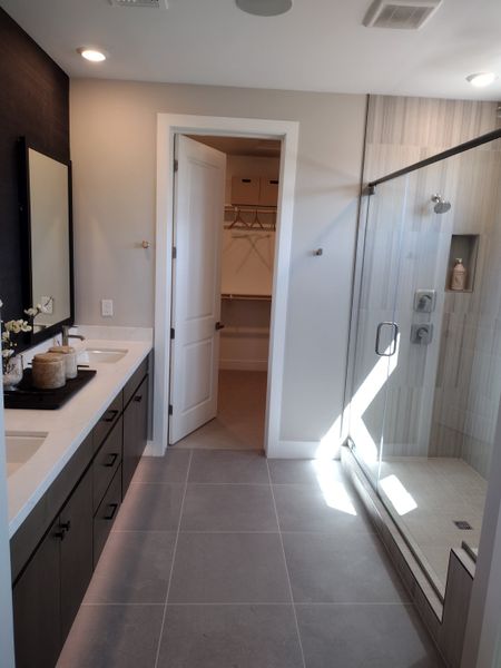 A sleek bathroom features dual sinks, a glass-enclosed shower, and elegant tilework, offering modern comfort and style.