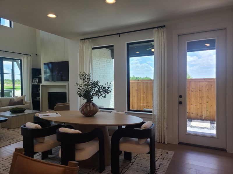 A modern living area with a cozy round table, stylish chairs, and large windows offering abundant natural light.