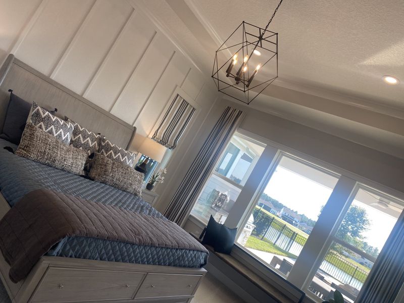 A serene bedroom with a chic geometric chandelier, large windows offering scenic views, and modern, stylish decor.