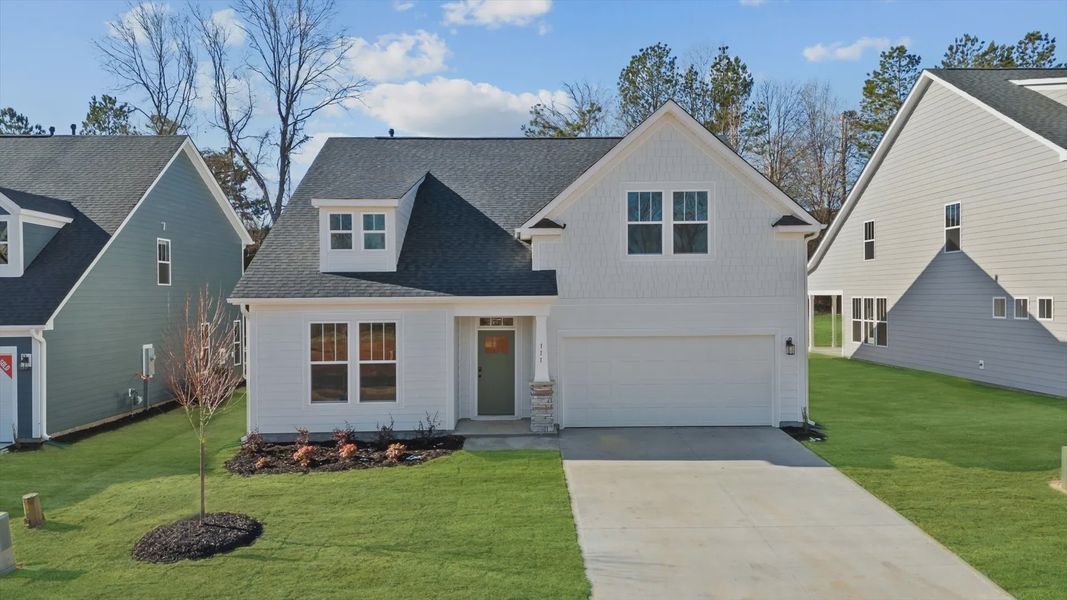 Stunning, bright, white exterior ranch style home with two car garage and stone columns at Pelham Crossing by DRB Homes