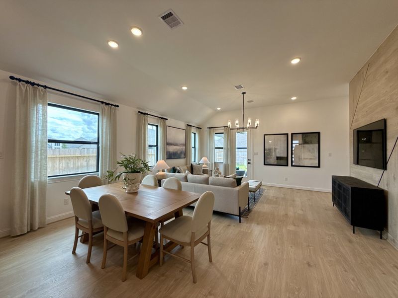 An open-concept living space featuring wood floors, elegant lighting, and large windows with natural light. An open-concept living space featuring wood floors, elegant lighting, and large windows with natural light.
