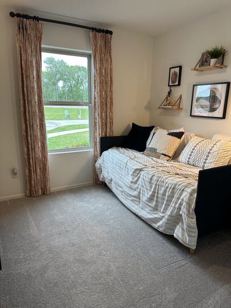 A cozy room with a daybed, patterned curtains, plush carpet, and decorative shelves on a neutral wall. A cozy room with a daybed, patterned curtains, plush carpet, and decorative shelves on a neutral wall.