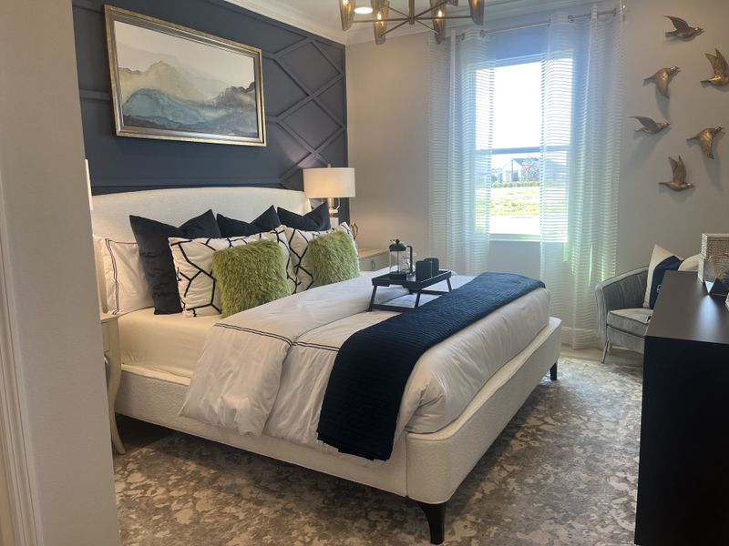 A cozy bedroom featuring a statement wall, plush bedding, elegant decor, and ambient natural light through sheer curtains. A cozy bedroom featuring a statement wall, plush bedding, elegant decor, and ambient natural light through sheer curtains.