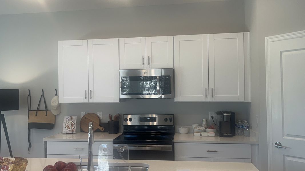 A modern kitchen with sleek white cabinets, stainless steel appliances, and minimalist decor.