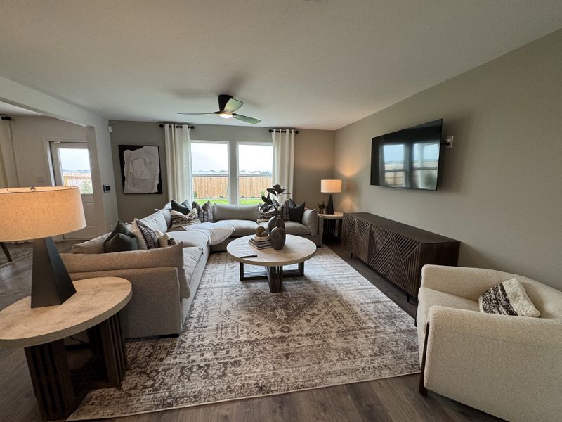 A cozy living area with a large sectional sofa, stylish decor, and a wall-mounted TV, filled with natural light and soothing tones.