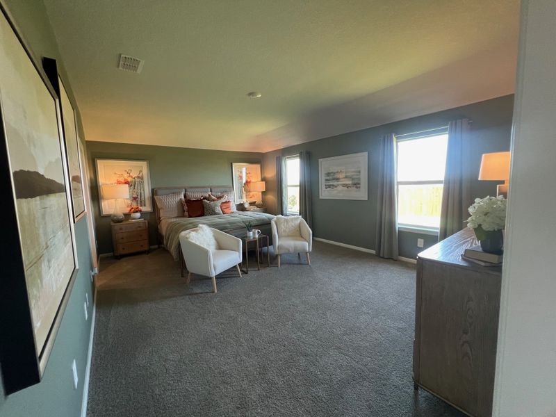 A spacious bedroom with cozy seating, elegant decor, and warm natural light from large windows. A spacious bedroom with cozy seating, elegant decor, and warm natural light from large windows.