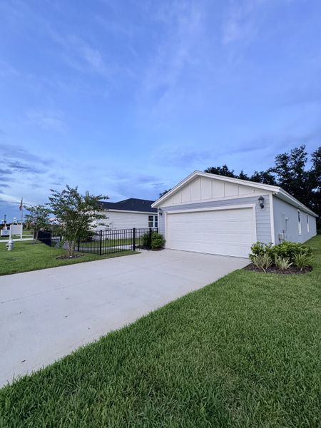A charming white home with a spacious driveway and manicured lawn in Lakes at Bella Lago by Meritage Homes (Green Cove Springs, FL).