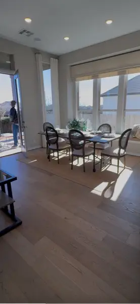 A bright dining area with wooden floors, large windows, and elegant seating, offering a seamless indoor-outdoor experience.