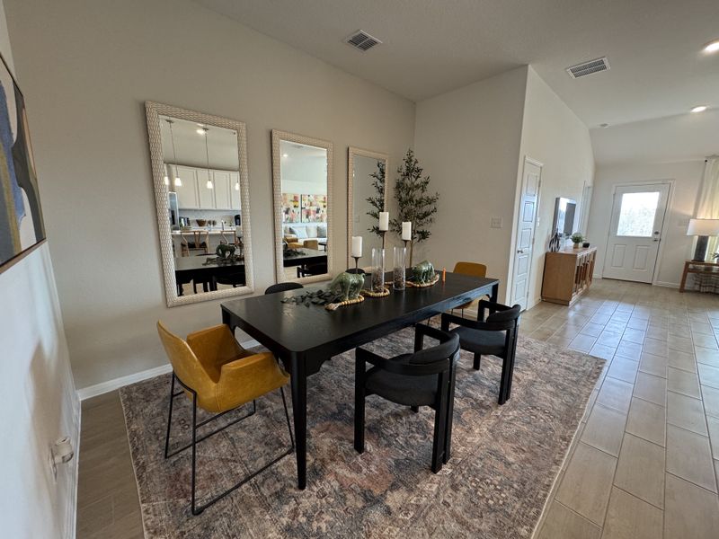 A stylish dining area features a sleek black table, modern chairs, and elegant decor, framed by large mirrors and soft lighting.