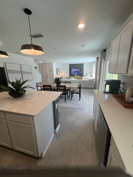 An open-concept living space featuring modern lighting, sleek countertops, and a cozy seating area with neutral tones.