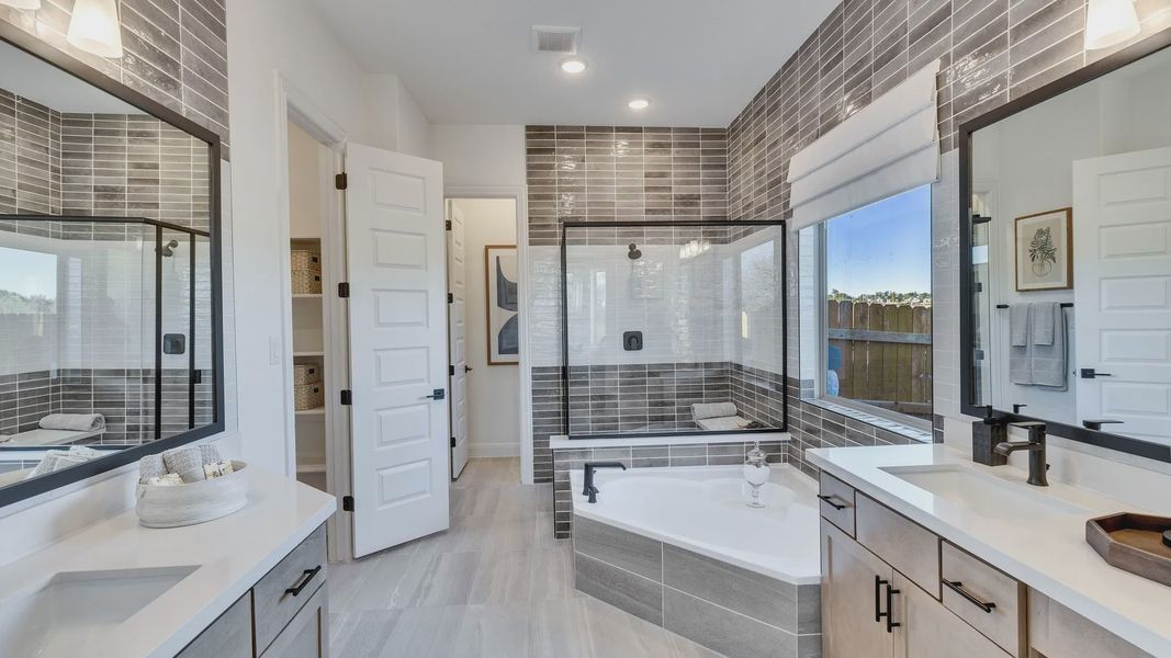 Exquisite gray tile and a sleek soaking tub define this high-end bathroom in Creeks Crossing.
