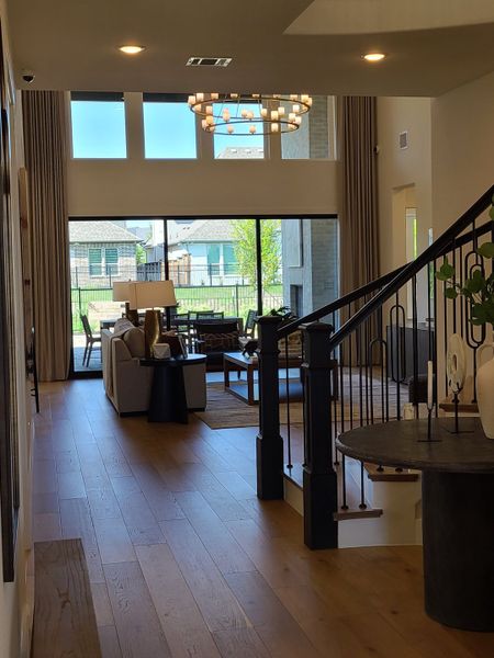 A contemporary living area featuring a grand chandelier, spacious window views, and elegant wood flooring. A contemporary living area featuring a grand chandelier, spacious window views, and elegant wood flooring.