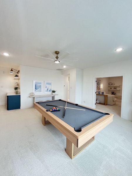 A modern game room with a sleek pool table, art-adorned walls, and cozy seating alcove for entertainment. A modern game room with a sleek pool table, art-adorned walls, and cozy seating alcove for entertainment.