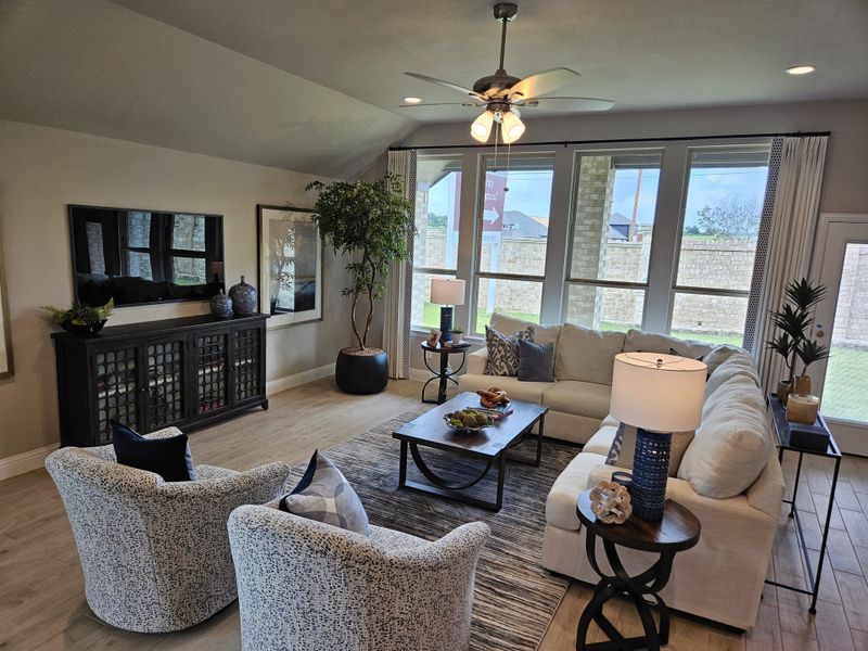 A cozy living room with plush seating, a large window, stylish decor, and warm lighting. A cozy living room with plush seating, a large window, stylish decor, and warm lighting.