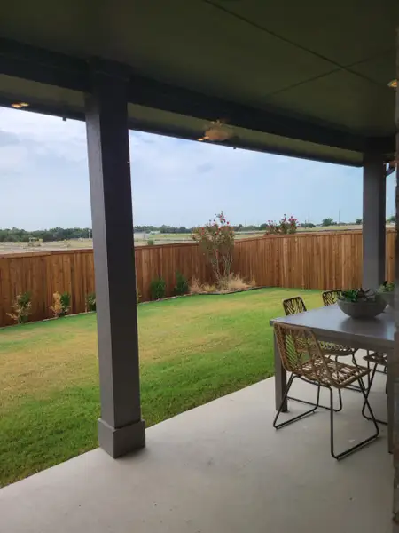 A cozy backyard patio with a modern dining set, overlooking a green lawn and wooden fence. A cozy backyard patio with a modern dining set, overlooking a green lawn and wooden fence.