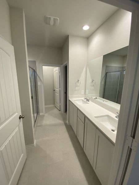 A modern bathroom featuring a double vanity, sleek cabinets, and a spacious shower with elegant neutral tones.