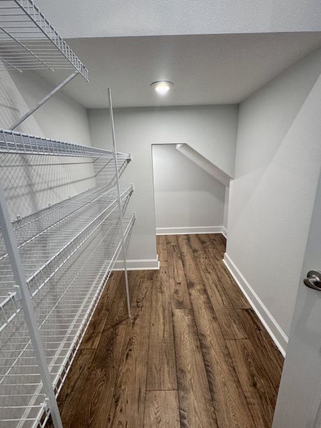 A spacious walk-in closet with sleek wire shelving and elegant wood flooring.