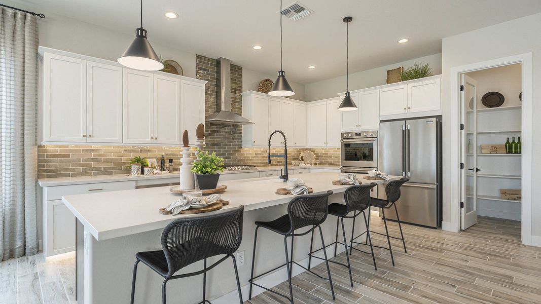 This Hacienda at Estrella kitchen features luxe white cabinetry, sophisticated island, and premium stainless-steel appliances.