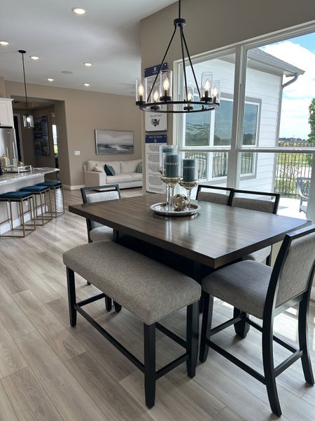A modern dining area with a sleek table, cozy seating, and stylish chandelier, featuring open views and natural light. A modern dining area with a sleek table, cozy seating, and stylish chandelier, featuring open views and natural light.