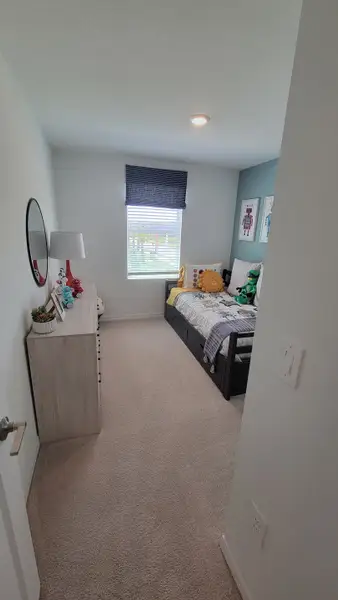 A cozy bedroom with a single bed, playful decor, and a light wood dresser, perfect for a child's retreat.