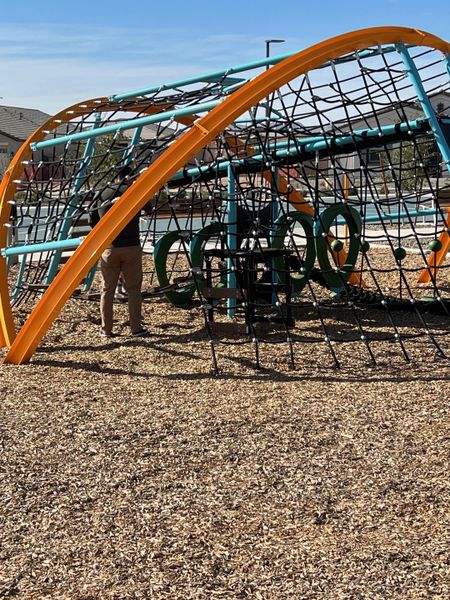 A modern playground with a colorful climbing structure in Tirreno at IronWing by Beazer Homes (Litchfield Park, AZ).