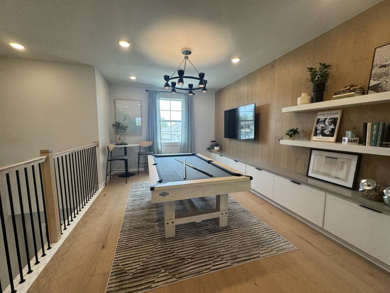 A modern game room featuring a sleek pool table, open shelving, and elegant decor under stylish lighting.