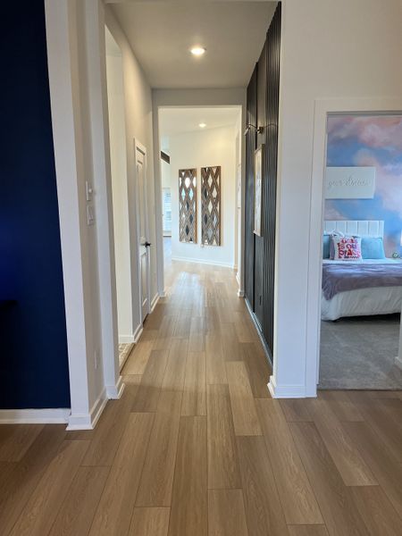 A modern hallway featuring sleek wood floors, bold navy accents, and contemporary wall art. A modern hallway featuring sleek wood floors, bold navy accents, and contemporary wall art.