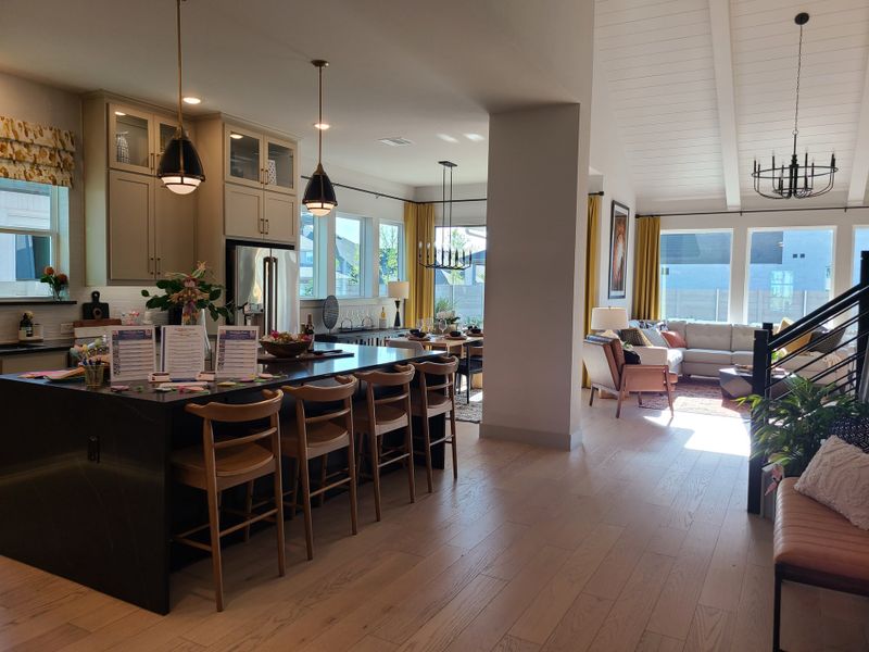 Open-concept kitchen and living area with a spacious island, modern lighting, and ample natural light. Luxurious and inviting.