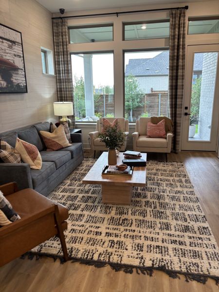 A cozy living room with a gray sofa, patterned rug, and large windows for ample natural light. A cozy living room with a gray sofa, patterned rug, and large windows for ample natural light.