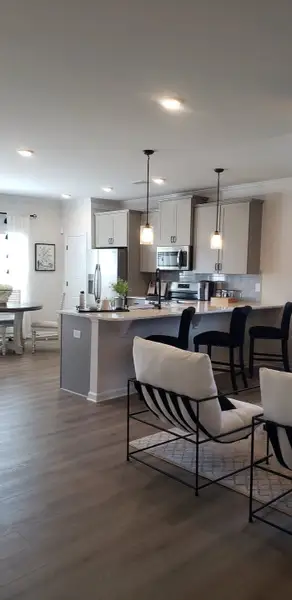 A modern kitchen featuring sleek cabinetry, an island with seating, and pendant lighting, seamlessly flowing into the dining area. A modern kitchen featuring sleek cabinetry, an island with seating, and pendant lighting, seamlessly flowing into the dining area.