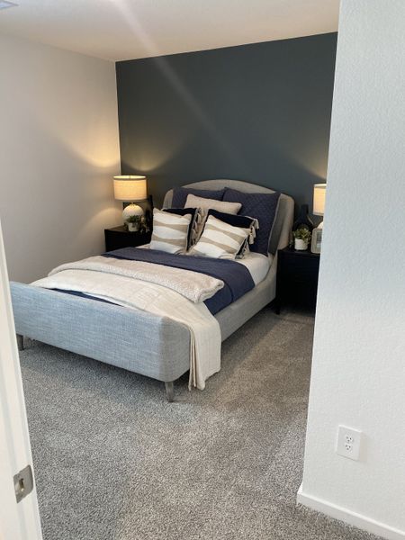 A stylish bedroom with a moody accent wall, plush bedding, and soft lighting for a relaxing ambiance.