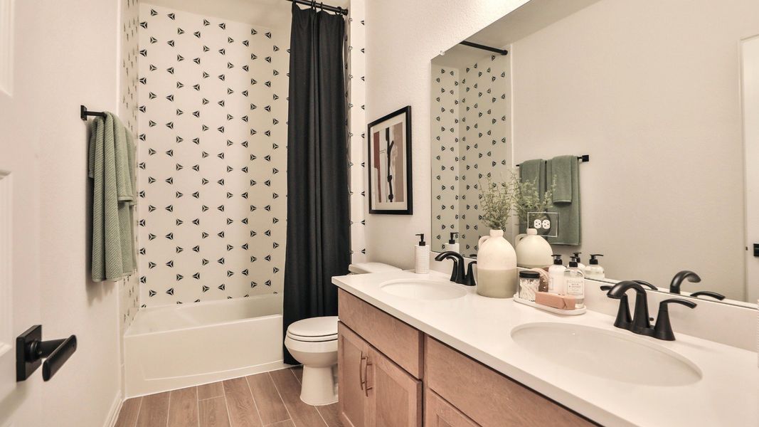Luxurious Bridgeland bathroom features striking geometric tiles, chic black fixtures, and dual sinks. Luxurious Bridgeland bathroom features striking geometric tiles, chic black fixtures, and dual sinks.