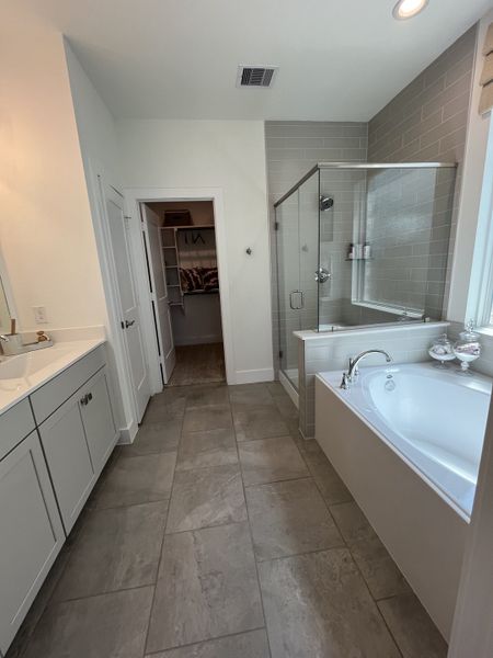 A modern bathroom featuring a glass shower, cozy bathtub, and sleek vanity with ample natural light.