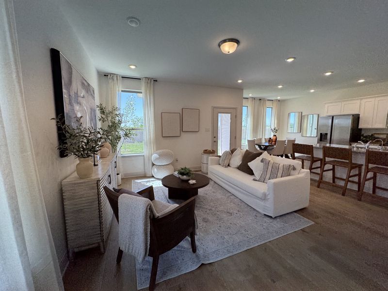A cozy living area with a white sofa, modern decor, and open kitchen featuring wooden accents and natural light. A cozy living area with a white sofa, modern decor, and open kitchen featuring wooden accents and natural light.
