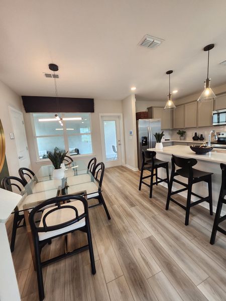 A modern kitchen-dining area with light wood flooring, sleek countertops, and stylish pendant lighting. A modern kitchen-dining area with light wood flooring, sleek countertops, and stylish pendant lighting.