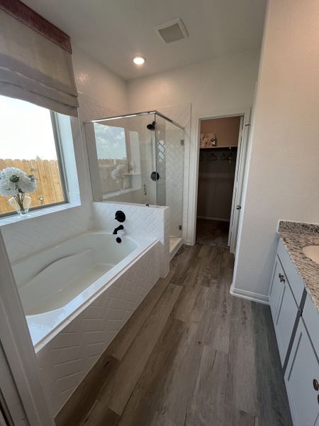 A modern bathroom featuring a sleek tub, wood grain flooring, and a spacious glass shower. A modern bathroom featuring a sleek tub, wood grain flooring, and a spacious glass shower.