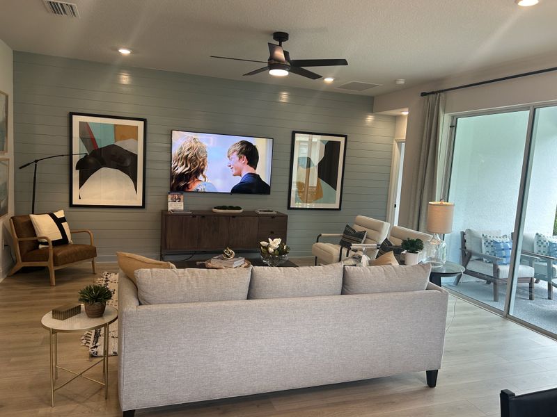 A stylish living room with a sleek modern layout, featuring abstract art, a cozy seating area, and large glass doors.