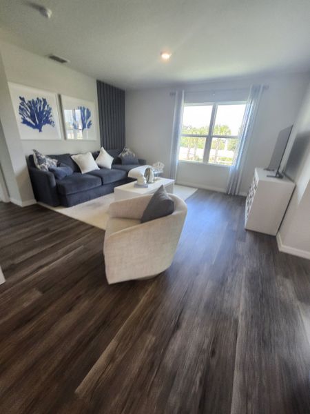 A cozy living room with a sleek navy sofa, abstract art, and rich wood flooring, offering a bright and inviting atmosphere.